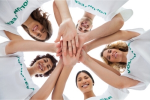 a team of volunteers showing unity, putting their hands together at the center